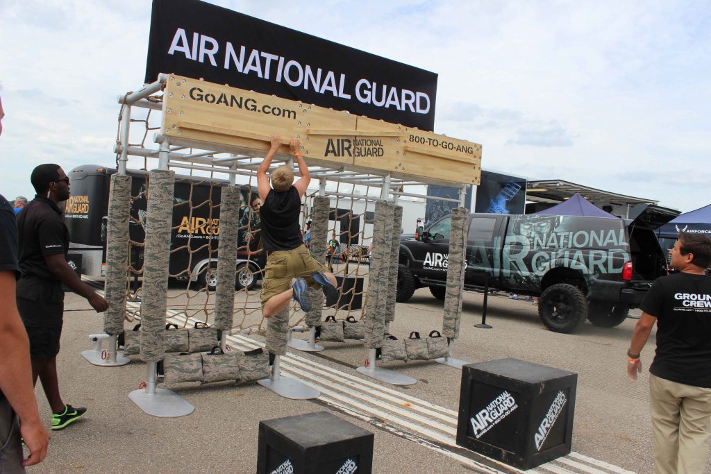 man completing a fingertip obstacle at an Air National Guard exhibit at an air show