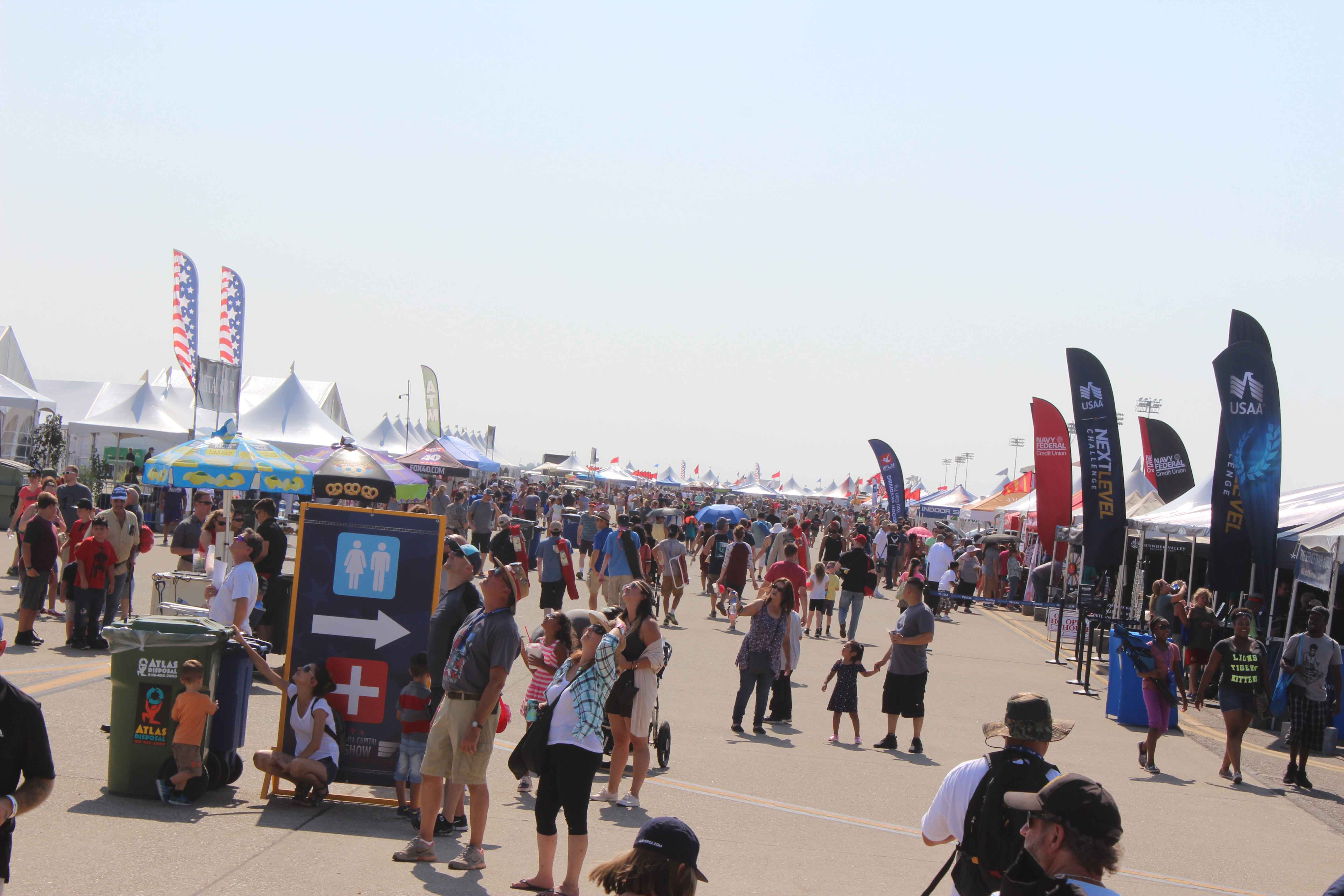 air show crowd surrounded by exhibits and VIP tents on the sides