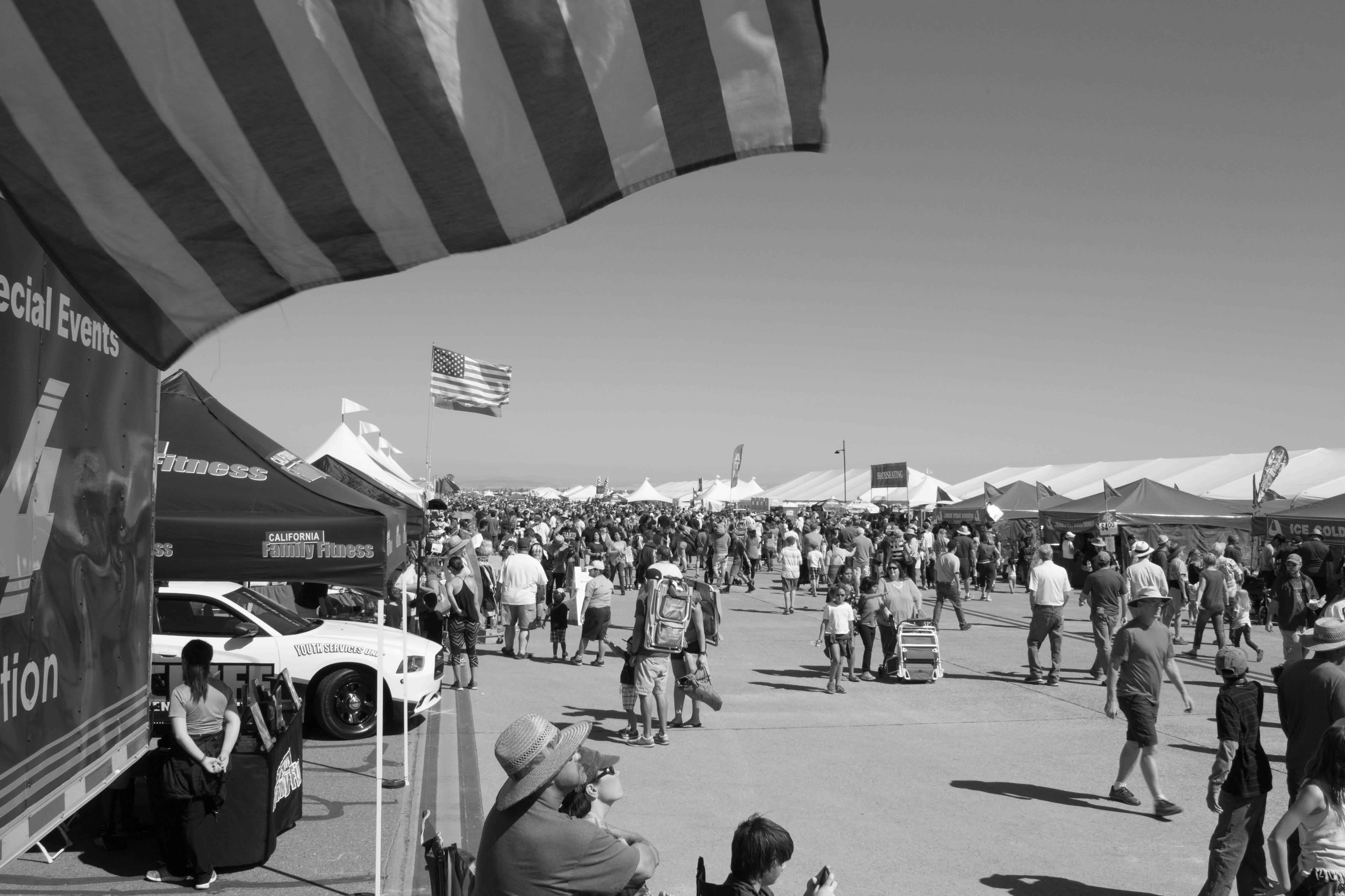 black and white photo of people walking around an air show