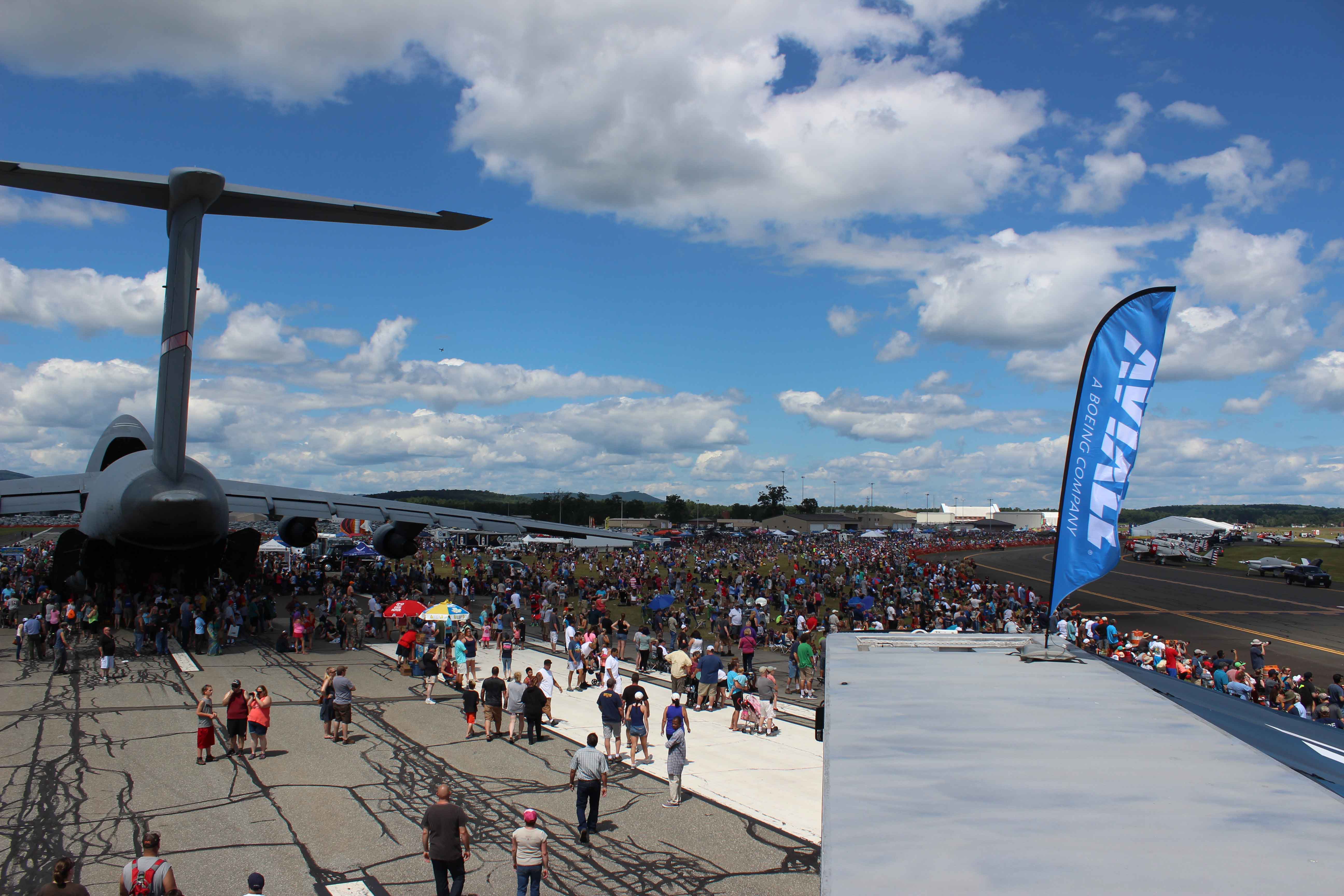 looking out from on top of a building out at a large air show crowd with a C5 airplane off to the left side