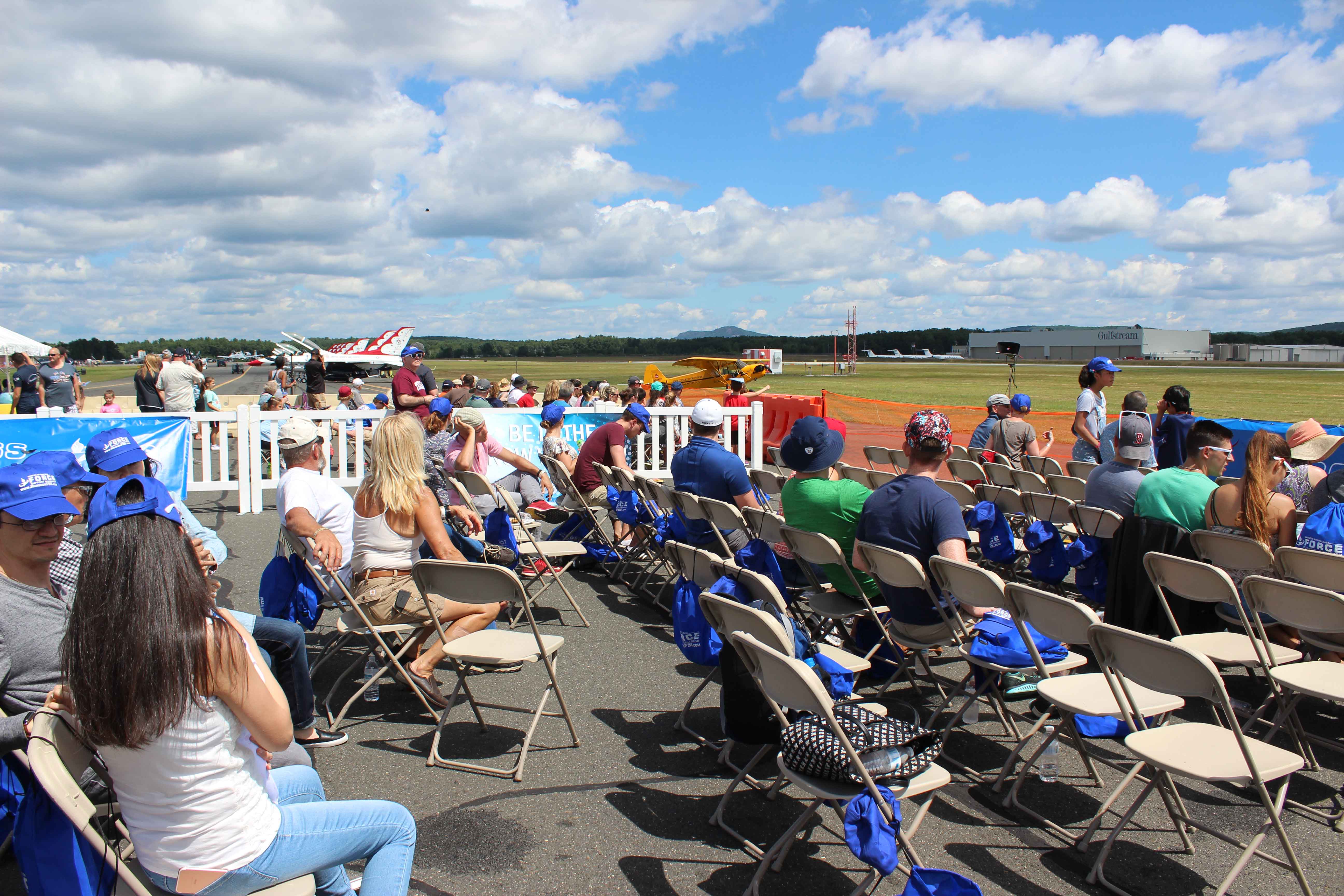 people sitting in chairs watching an air show at the show line
