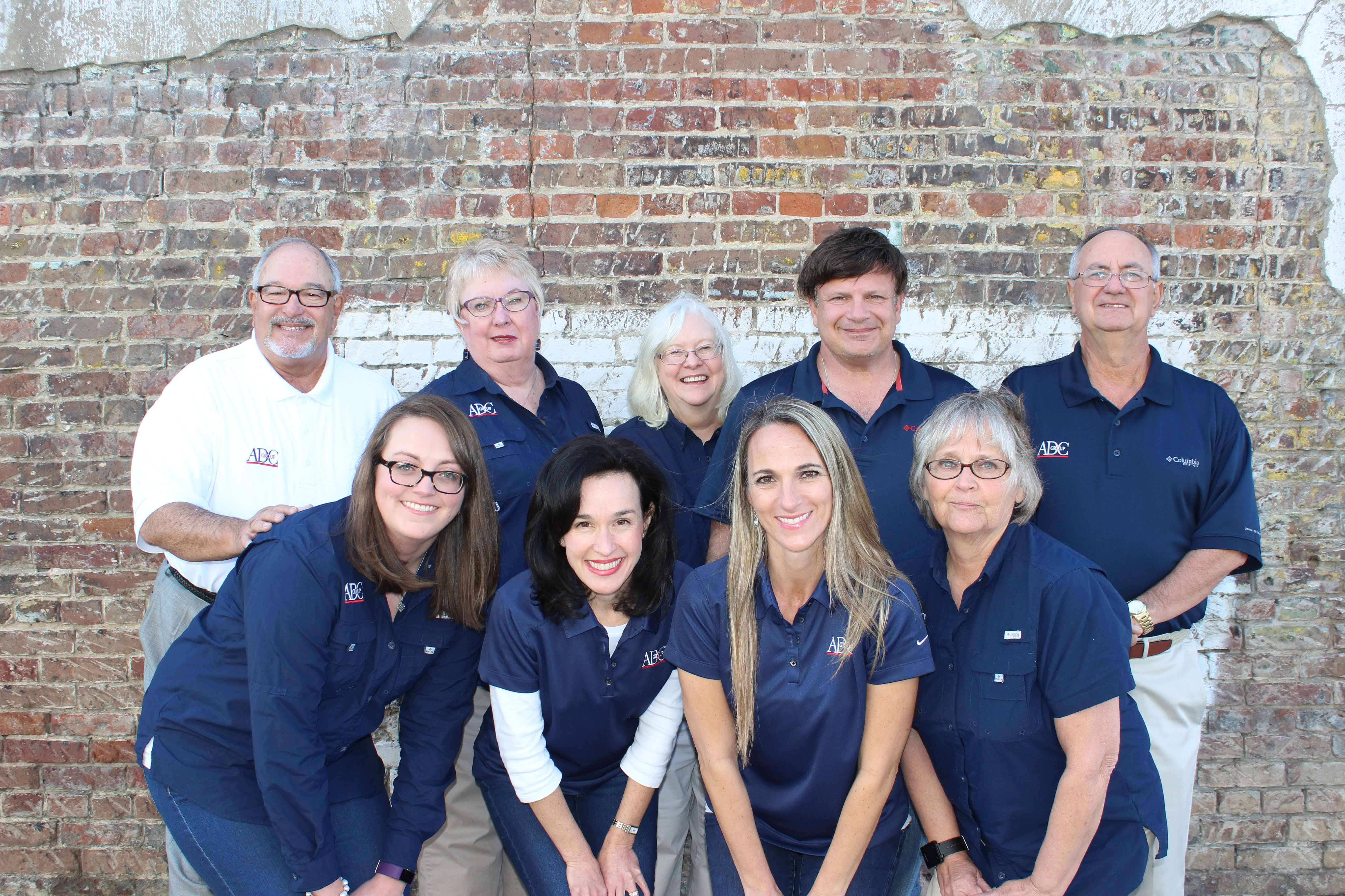 ADC Group team posing in front of a brick building