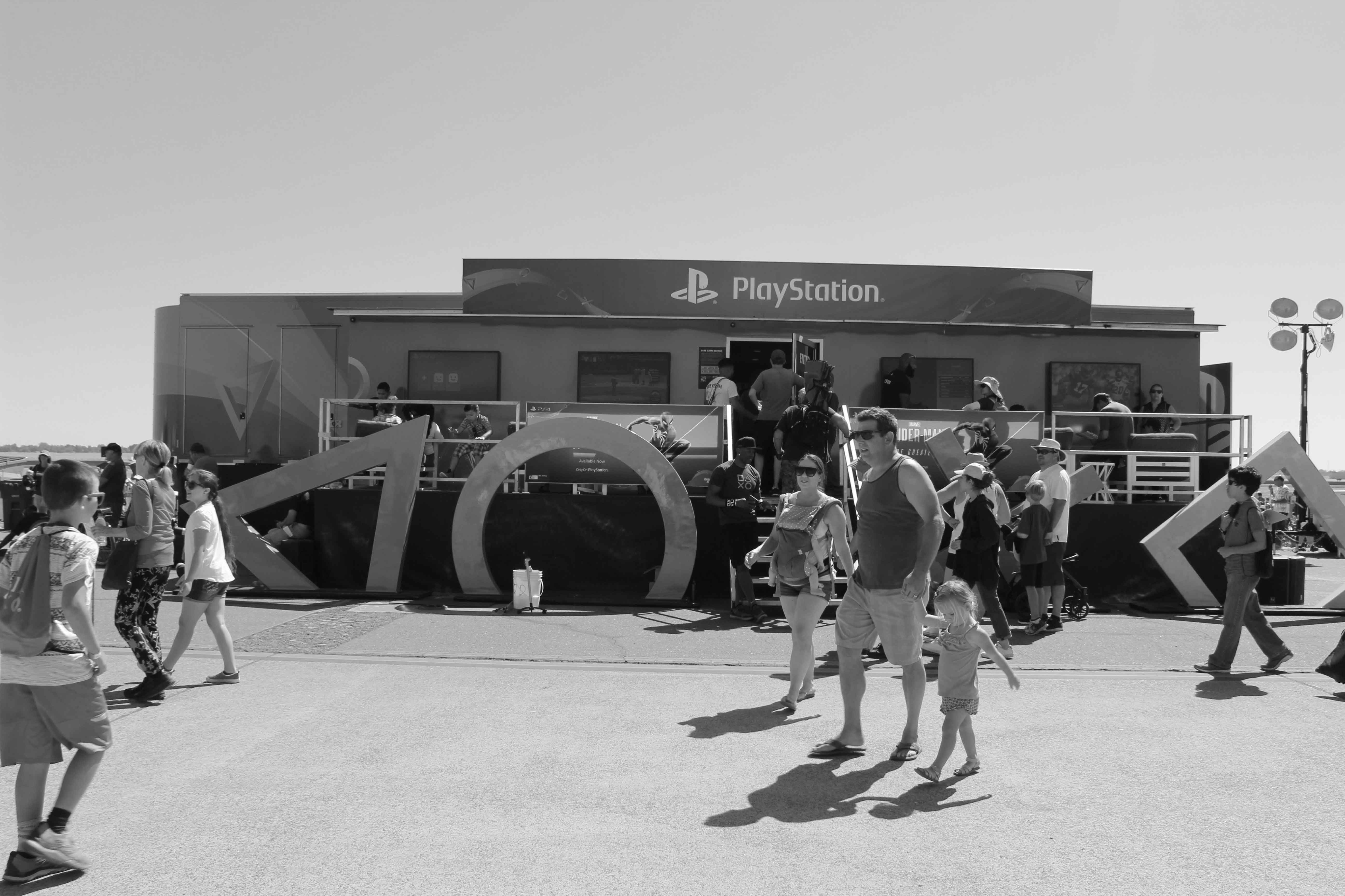 black and white photo of people walking by playstation exhibit at an air show