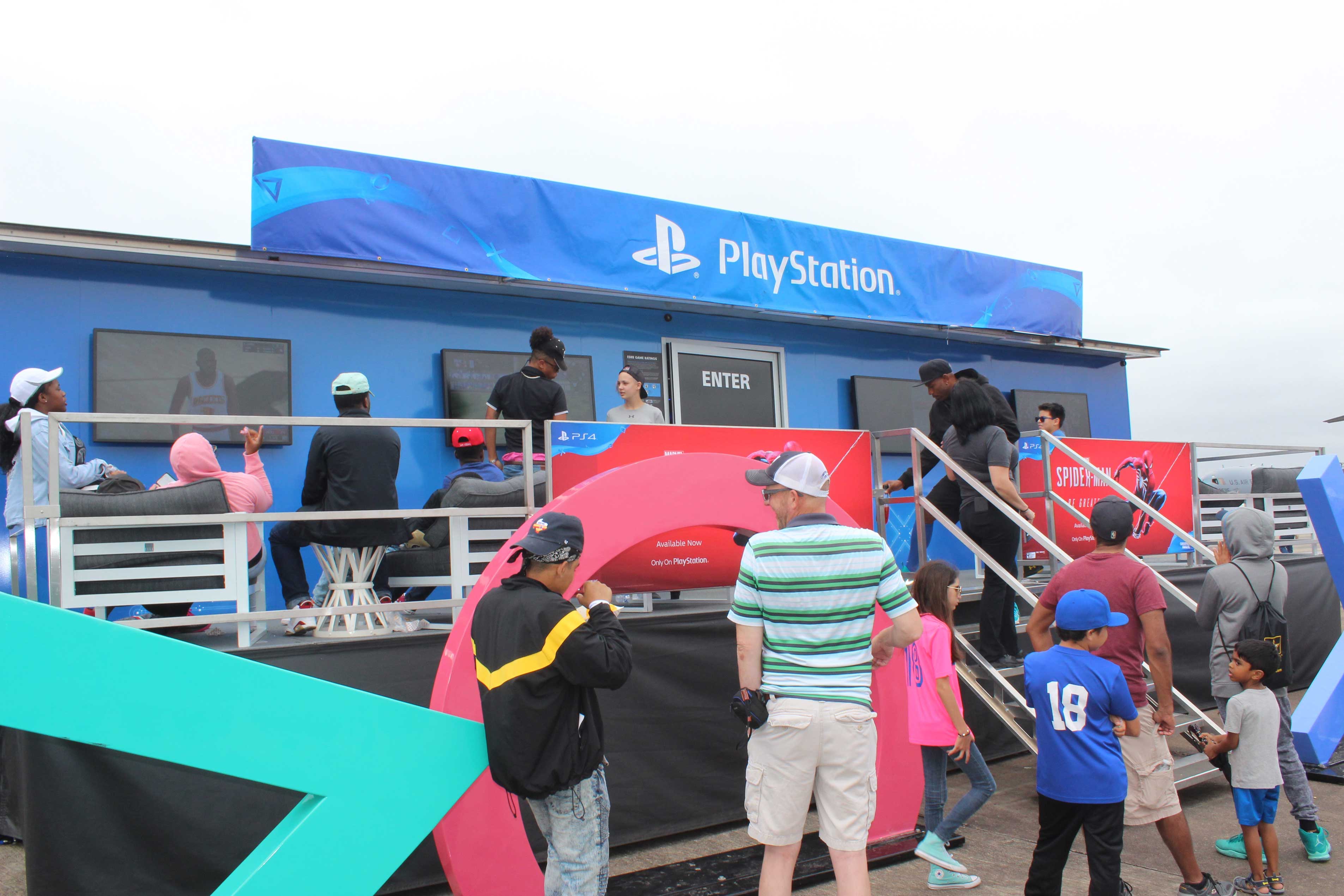 people entering and exiting playstation exhibit at an air show on a cloudy day