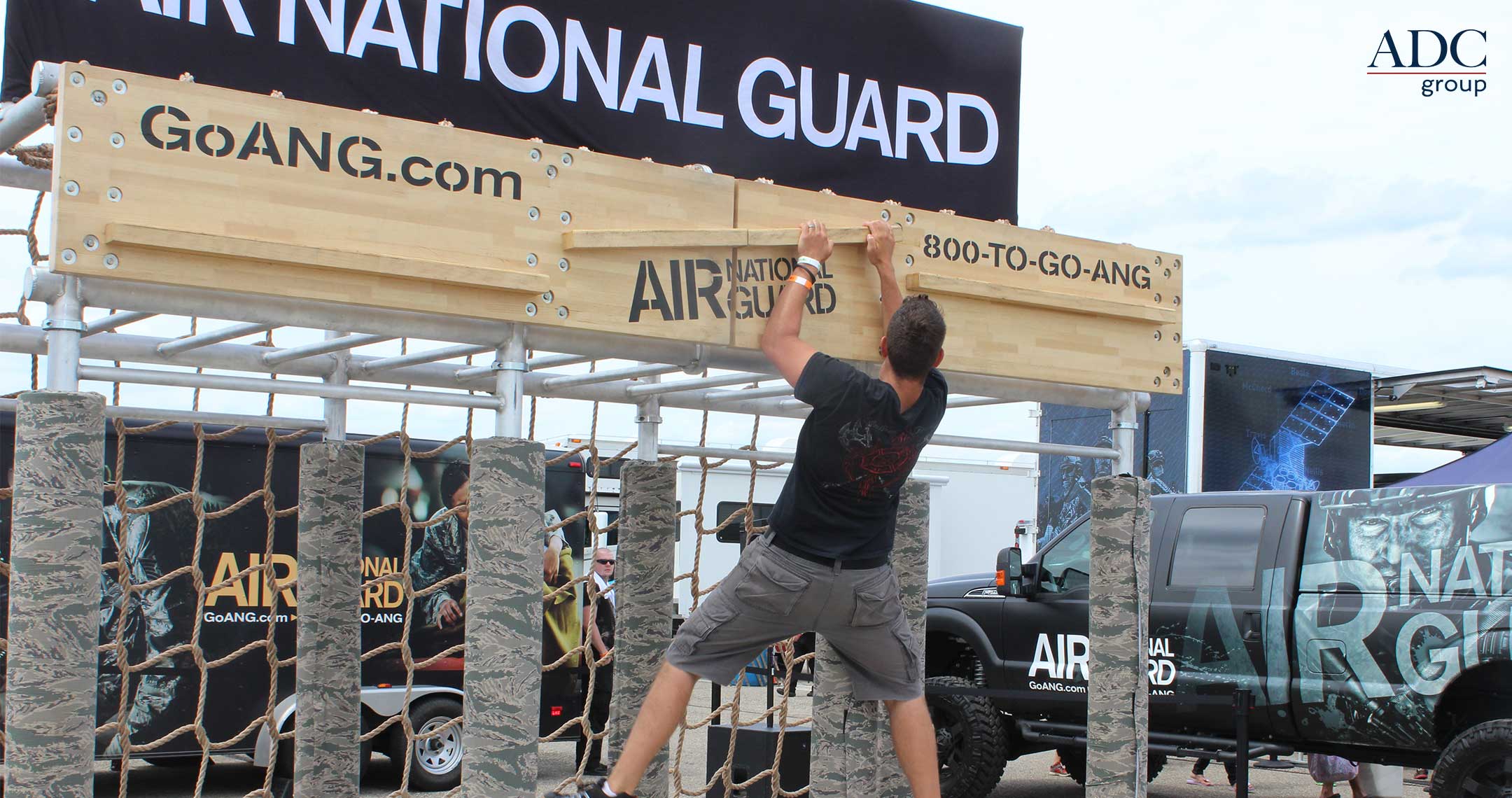 man climbing on obstacle course of Air National Guard mobile marketing exhibit at an air show